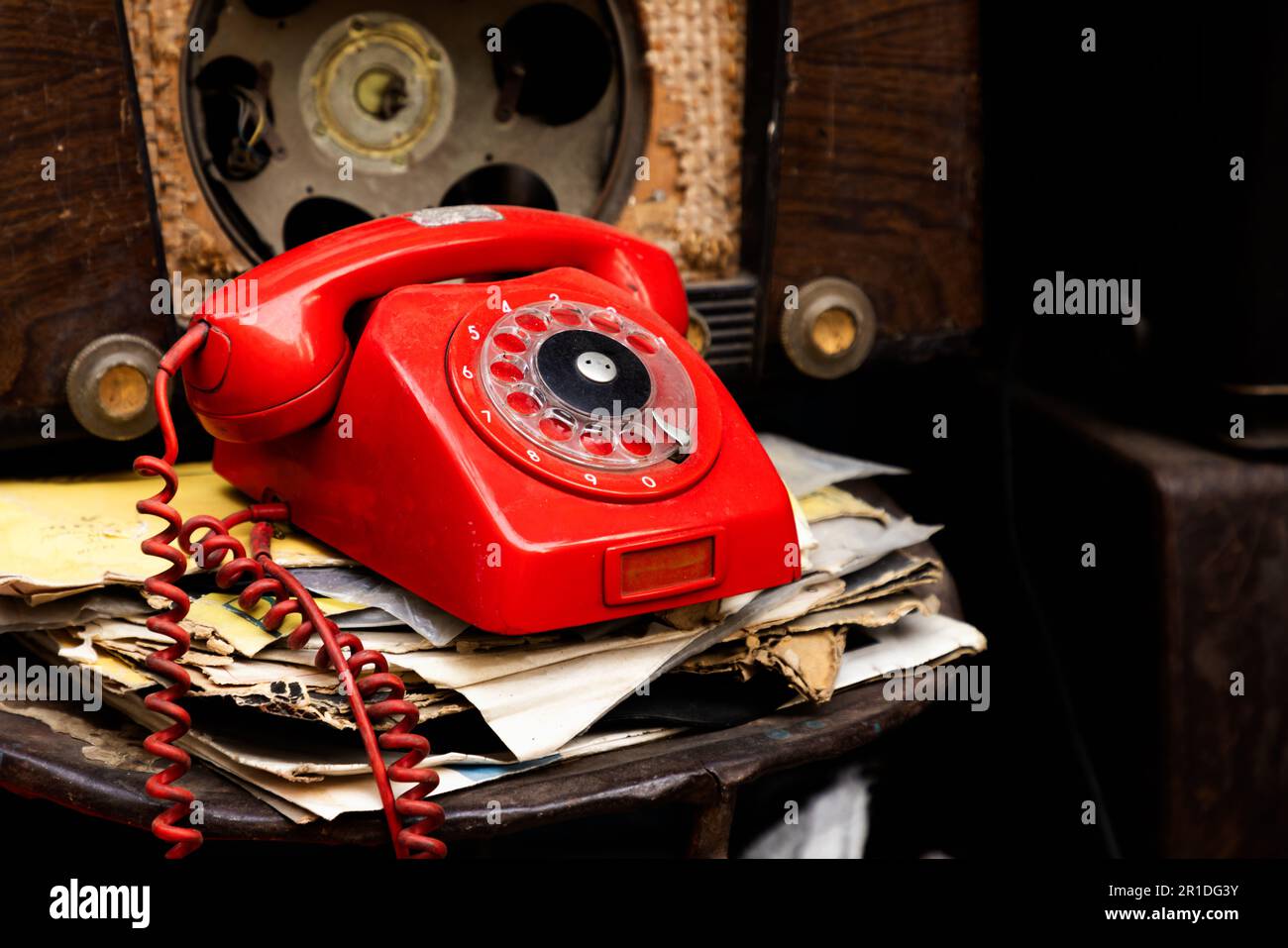 Altes rotes, antikes Telefon zwischen alten Radios und Zeitungen Stockfoto