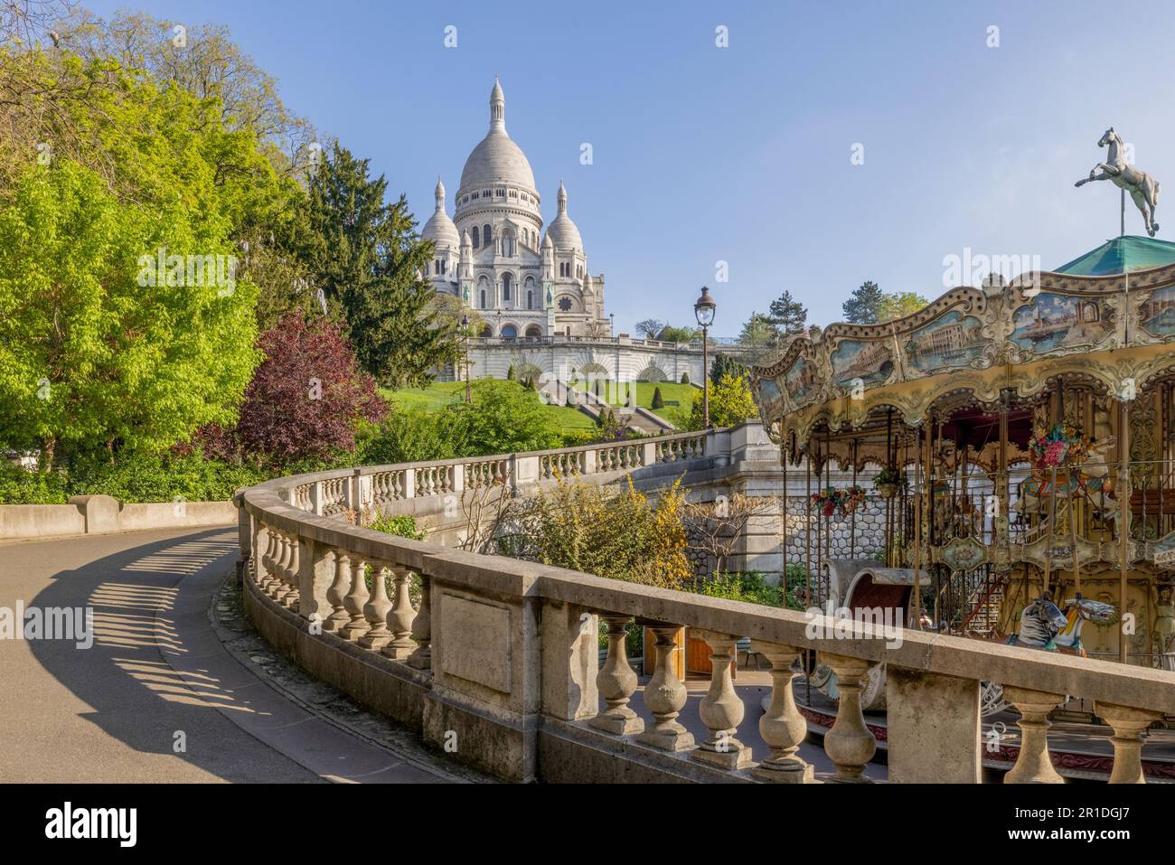 Gärten des Sacré-Cœur und traditionelles Karussell in Montmartre, Paris, mit gestalteten Treppen, die zur berühmten Basilika führen. Stockfoto