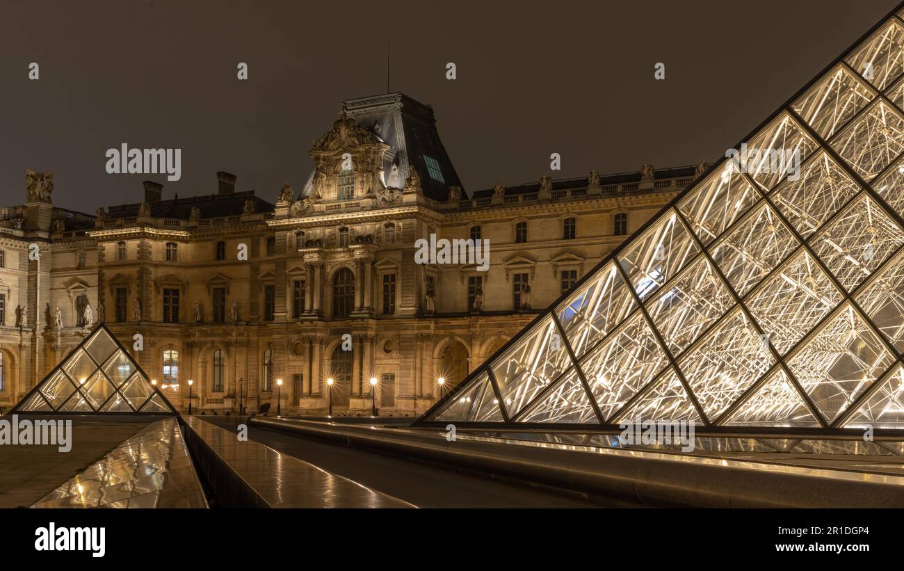 Der Louvre in Paris, Frankreich. Glaspyramiden bei Nacht im berühmten Museum. Stockfoto