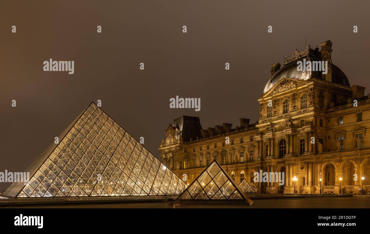 Der Louvre in Paris, Frankreich. Glaspyramiden bei Nacht im berühmten Museum. Stockfoto