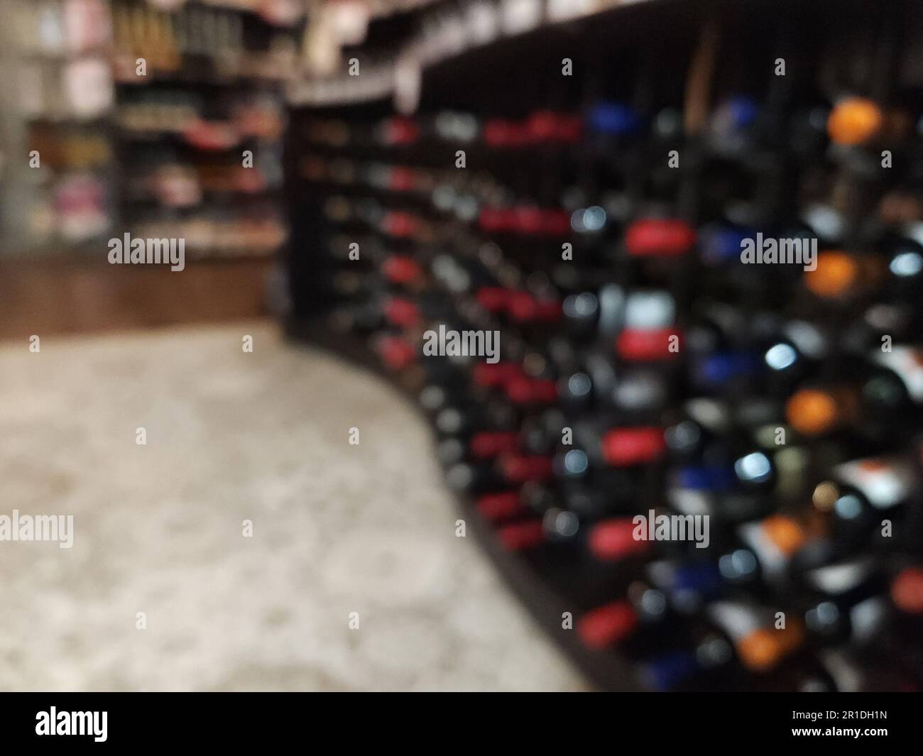 Unscharfer Hintergrund im Weinladen. Eine Reihe mit vielen Flaschen Wein Stockfoto