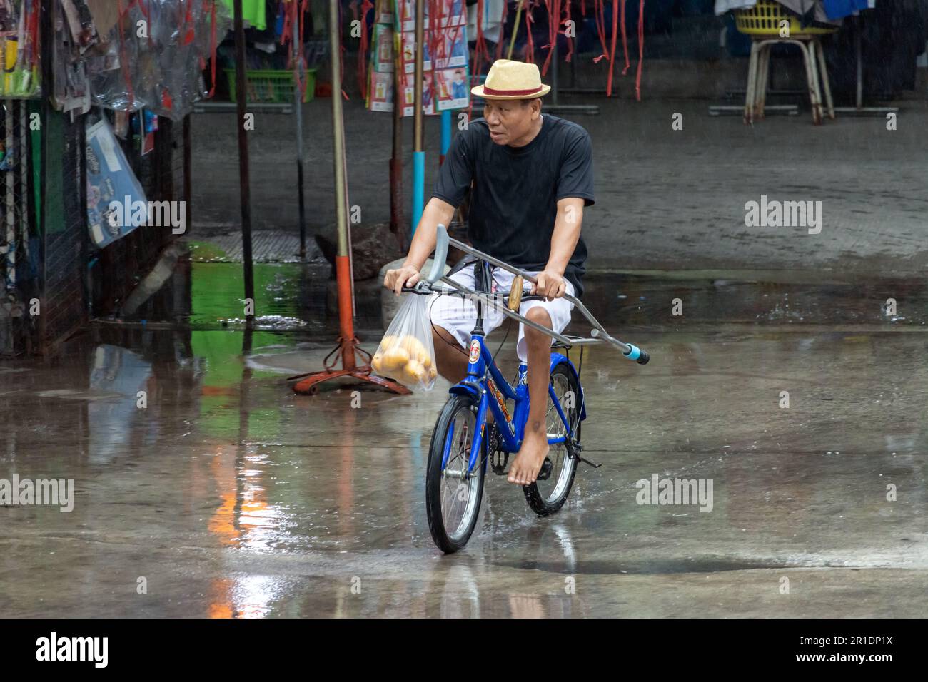 SAMUT PRAKAN, THAILAND, MAI 10 2023, Ein Mann, der auf einem Fahrrad in der Rainy Street fährt. Stockfoto