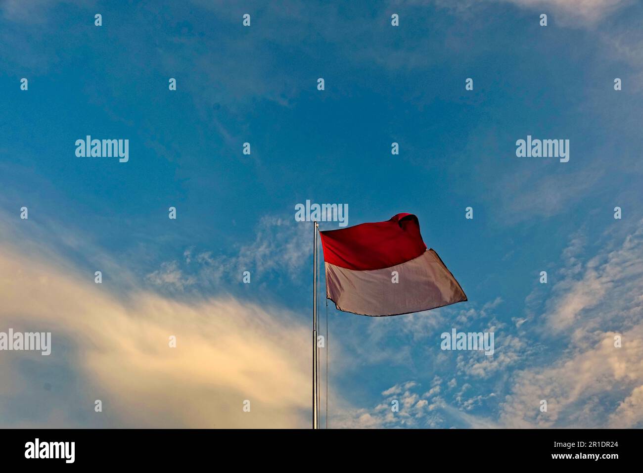 Die rote und weiße Fahnenstange flattert gegen den Himmel, die indonesische Flagge auf dem Pol gegen den Himmel Stockfoto