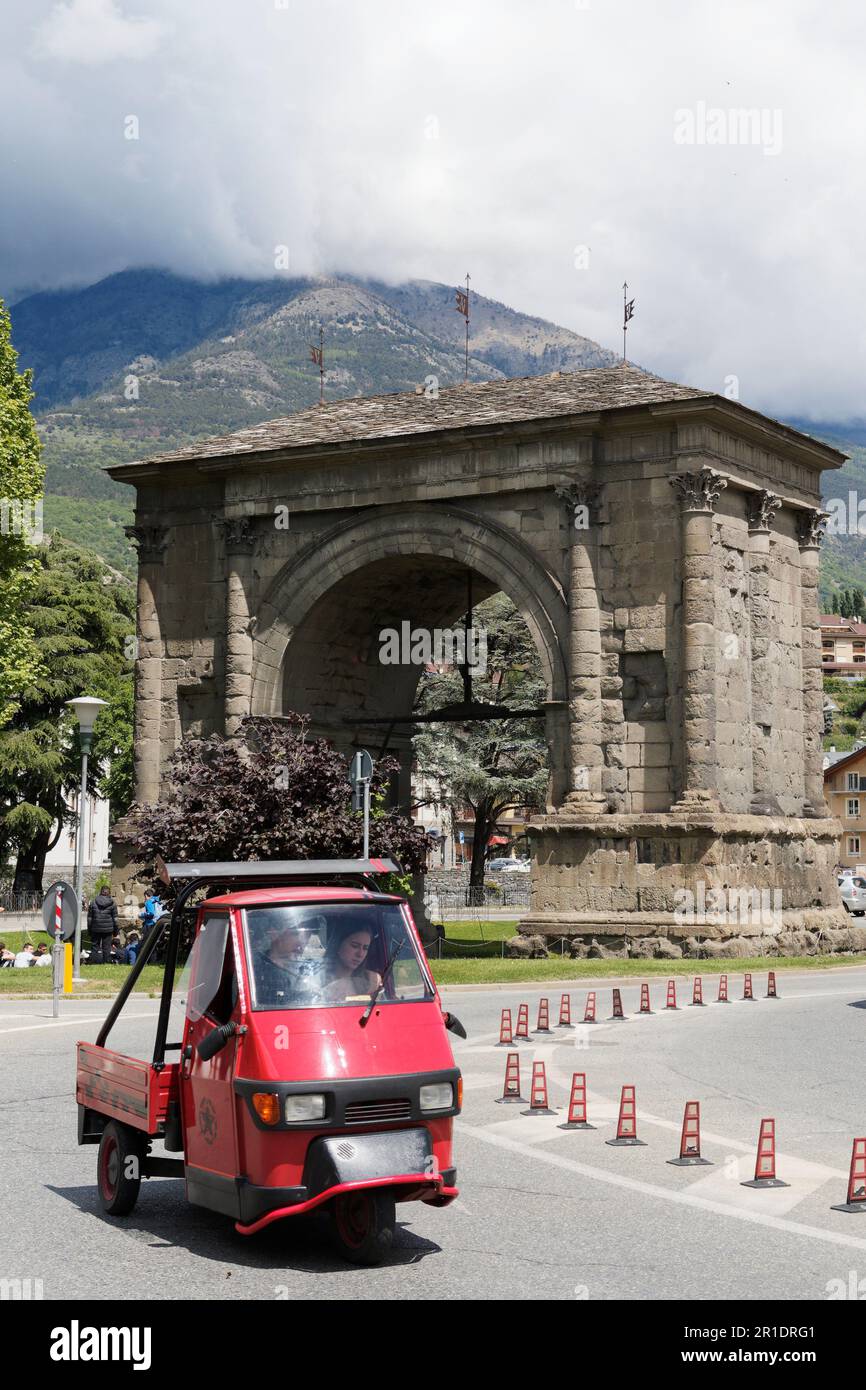 Ein Ape-Auto fährt vor dem Augustusbogen in Aosta City, Aosta Valley, NW Italien Stockfoto