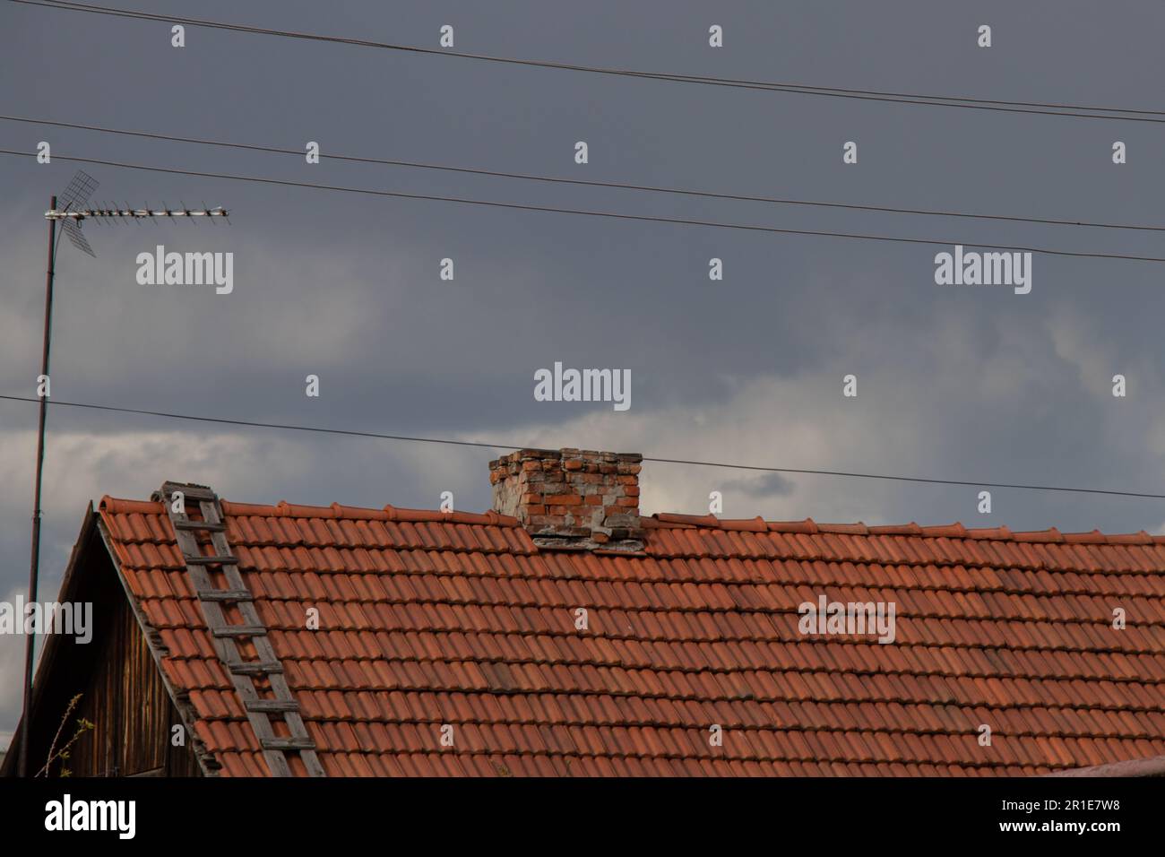 Das Dach eines alten einstöckigen Hauses aus rotem Schiefer am Himmel in der Ukraine Stockfoto