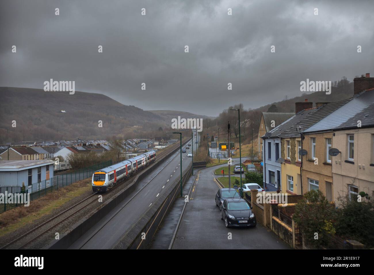 Transport nach Wales Klasse 170 turbostar Zug vorbei an Reihen von terrassenförmigen Häusern, während er an Cwm, Blaenau Gwent, Wales auf der Eisenbahnlinie Ebbw Vale vorbeifährt Stockfoto