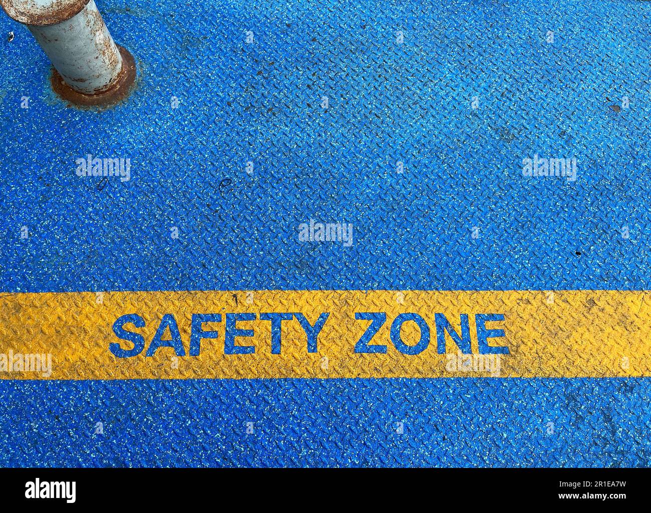Die Textmarke gelbe Sicherheitszone auf Stahlboden mit blauer Grunge-Asphaltoberfläche. Schild für den Beifahrer, um Gefahren durch Verkehr und Fahrzeugbewegungen zu erkennen Stockfoto