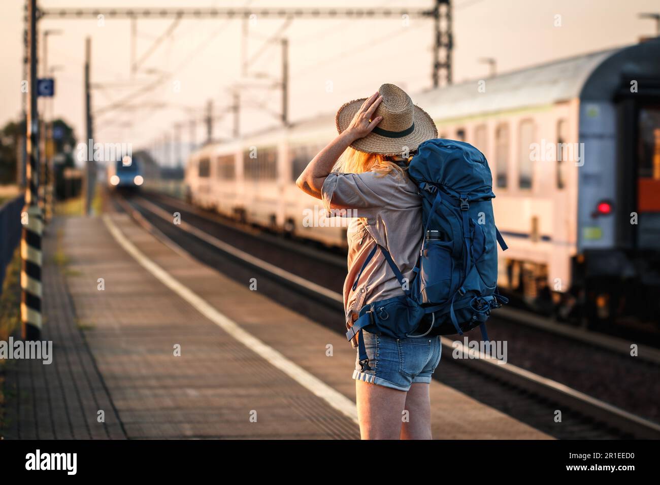 Fahren Sie mit dem Zug. Eine Frau, die am Bahnhof steht und auf den ankommenden Zug schaut Stockfoto