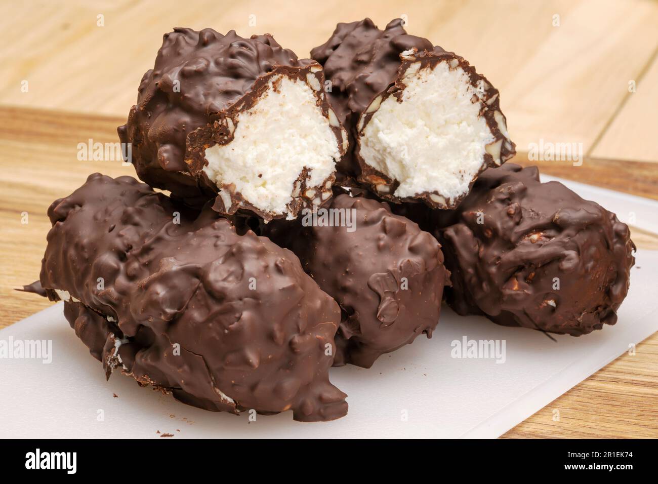 Natürlicher Dessert-Hüttenkäse in Schokolade mit Walnüssen auf einem Holztisch Stockfoto