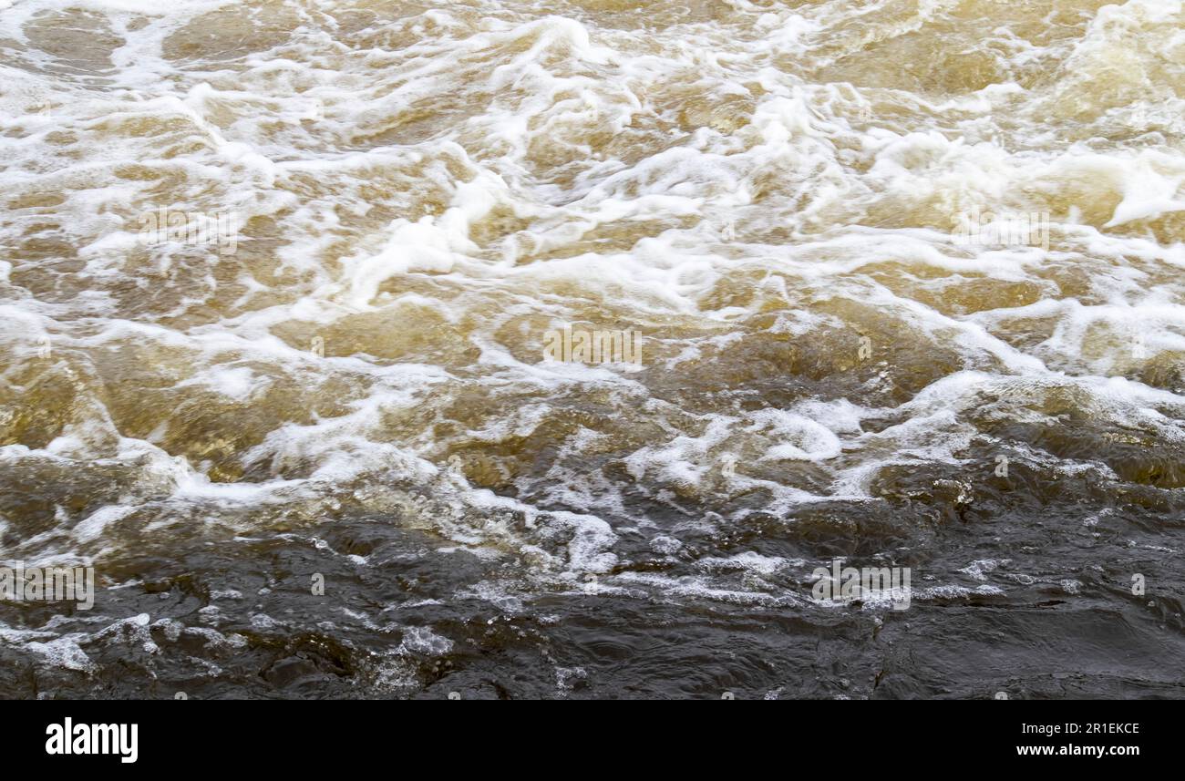 Stromschnellen. Nahaufnahme des abstrakten Hintergrunds von fallendem Wasser. Das Wasser fließt über die Felsen des Flusses. Ein wunderschöner, mächtiger Fluss eines stürmischen Bergflusses. Die Stockfoto