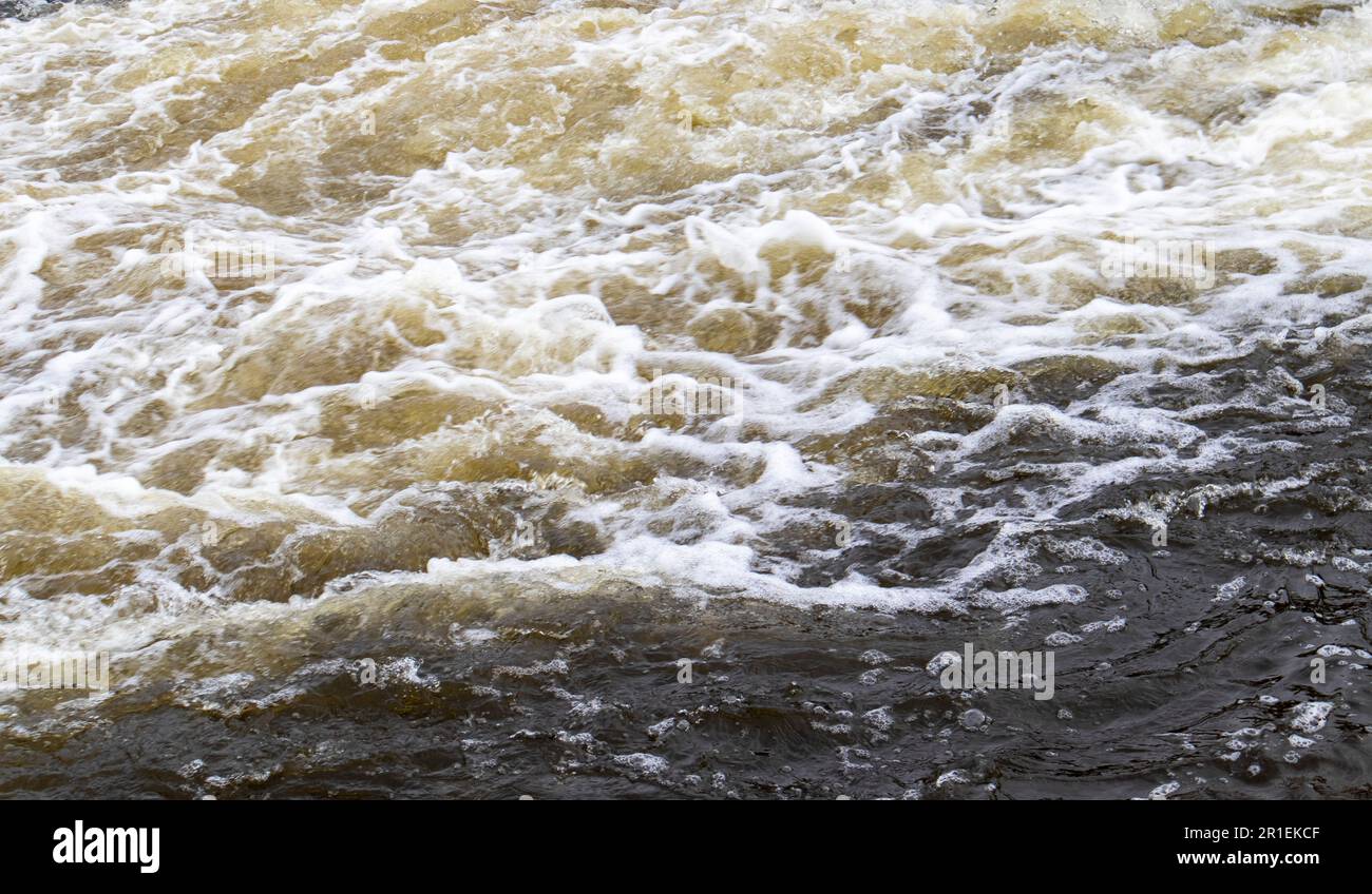 Stromschnellen. Nahaufnahme des abstrakten Hintergrunds von fallendem Wasser. Das Wasser fließt über die Felsen des Flusses. Ein wunderschöner, mächtiger Fluss eines stürmischen Bergflusses. Die Stockfoto