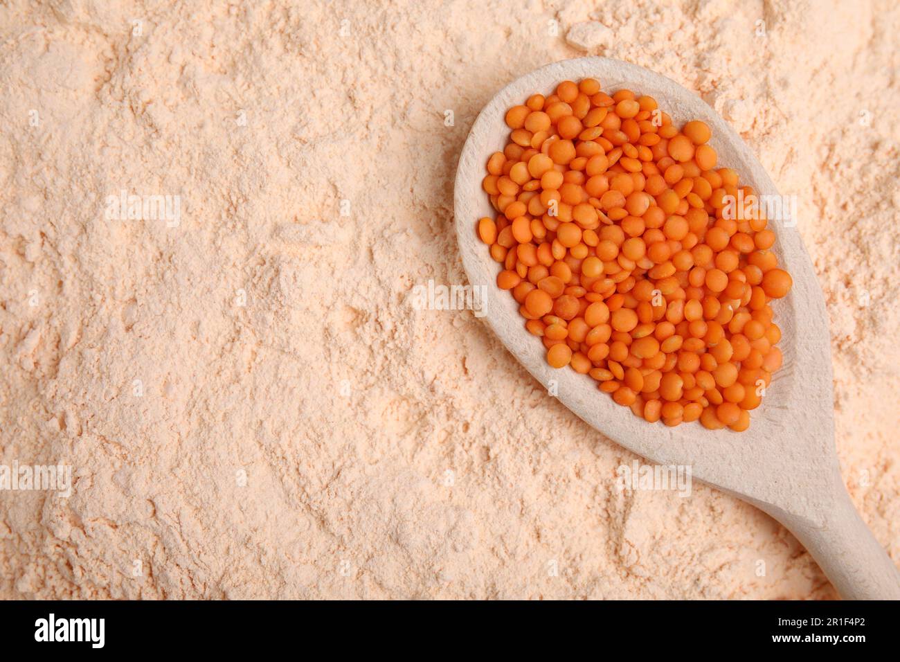 Löffel mit Linsenkörnern auf Mehl, Draufsicht. Platz für Text Stockfoto