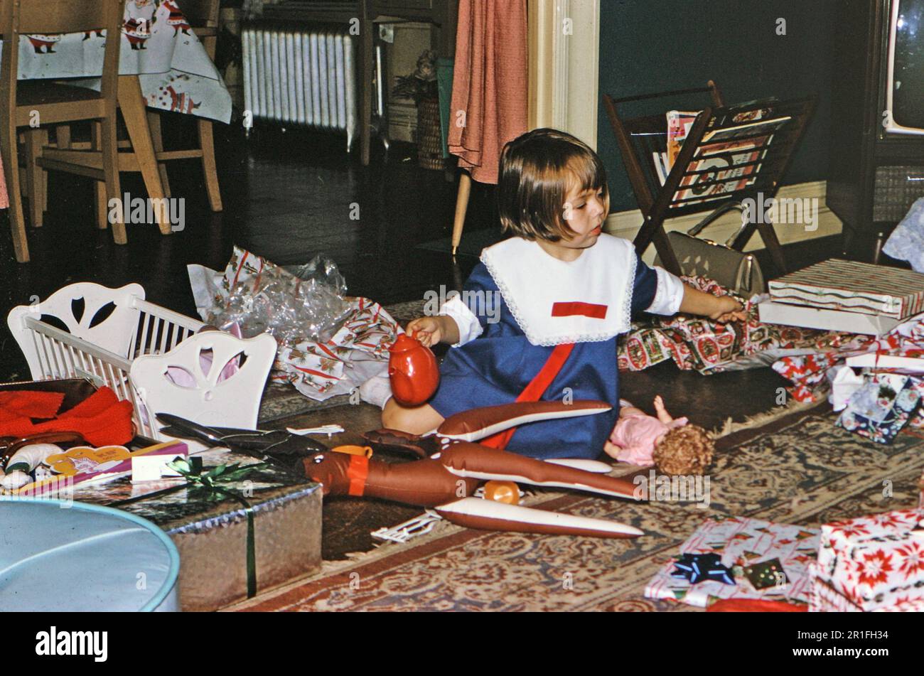 Ein junges Mädchen öffnet Geschenke am Weihnachtsmorgen ca. 1965 Stockfoto