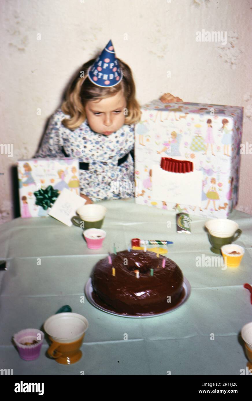 Geburtstagskind bläst Kerzen auf ihrem Geburtstagskuchen aus. 1969 Stockfoto