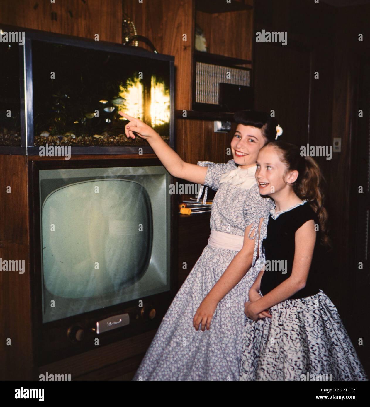 Ein junges Mädchen zeigt auf einen Fisch in einem Panzer auf einem Fernseher im Haus ihrer Großmutter in Arkansas, Ca. 1958 Stockfoto