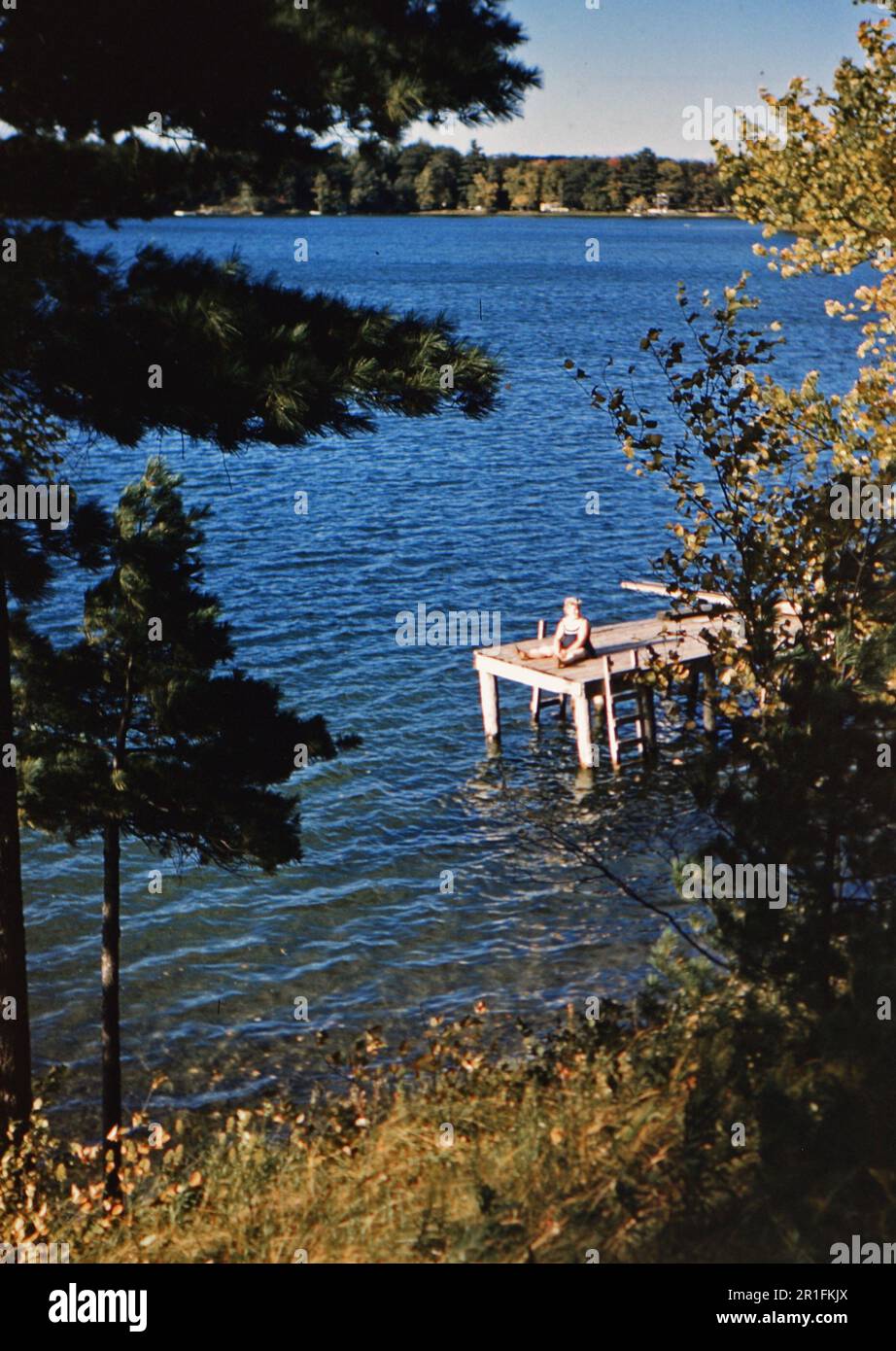 Ein Mädchen, das auf einem Dock an einem See sitzt. 1958 Stockfoto