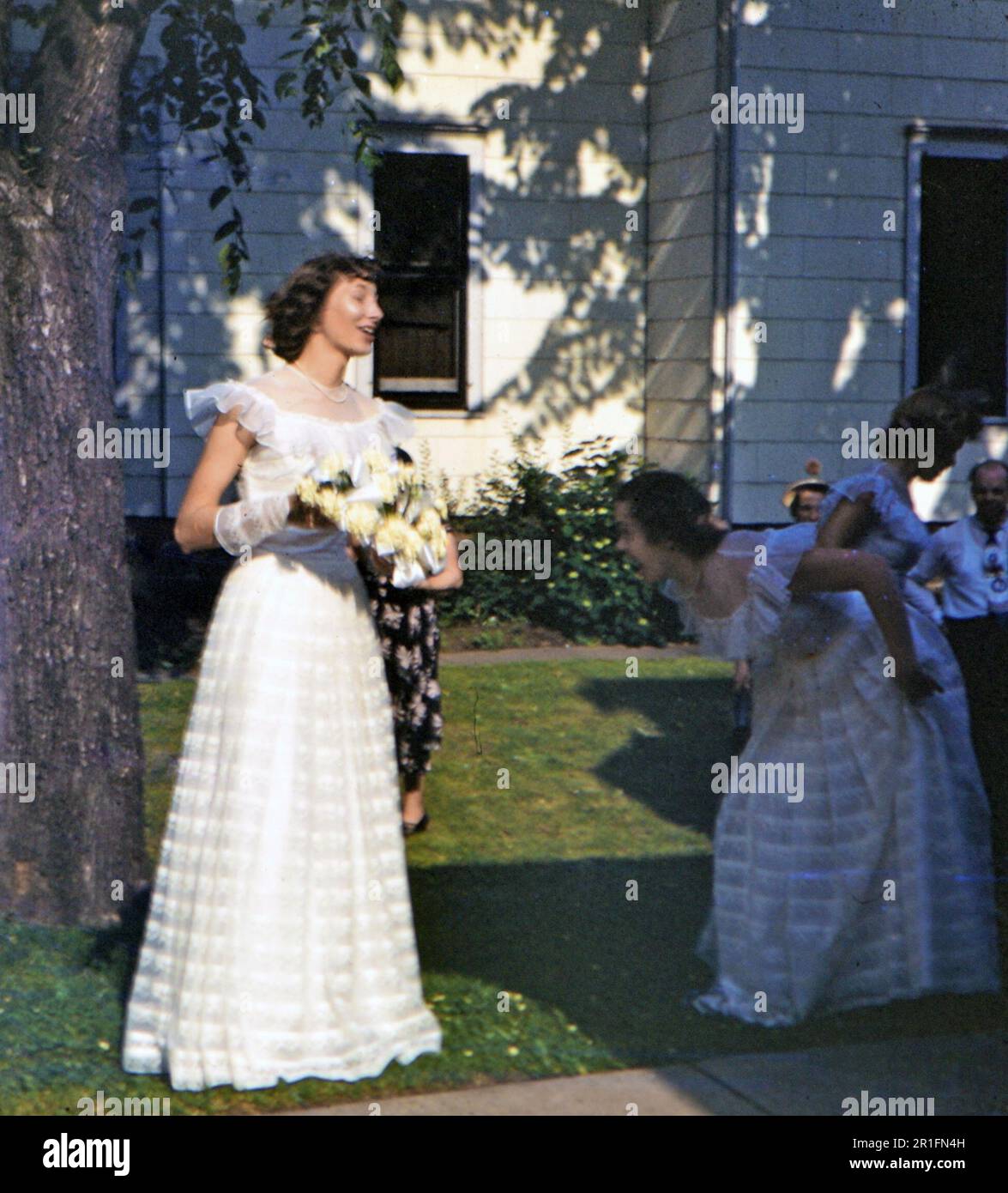 Eine Frau im Hochzeitskleid und eine Brautjungfer oder ein Blumenmädchen, die mit ihrem (r) Ca. 1950-1955 Stockfoto