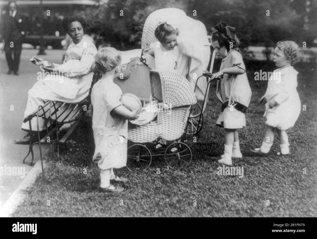 Vier kleine Kinder, die in Washington, D.C. mit Kinderwagen spielen, Park - afroamerikanische Kindermädchen, die mit Baby Ca. 1920 Stockfoto