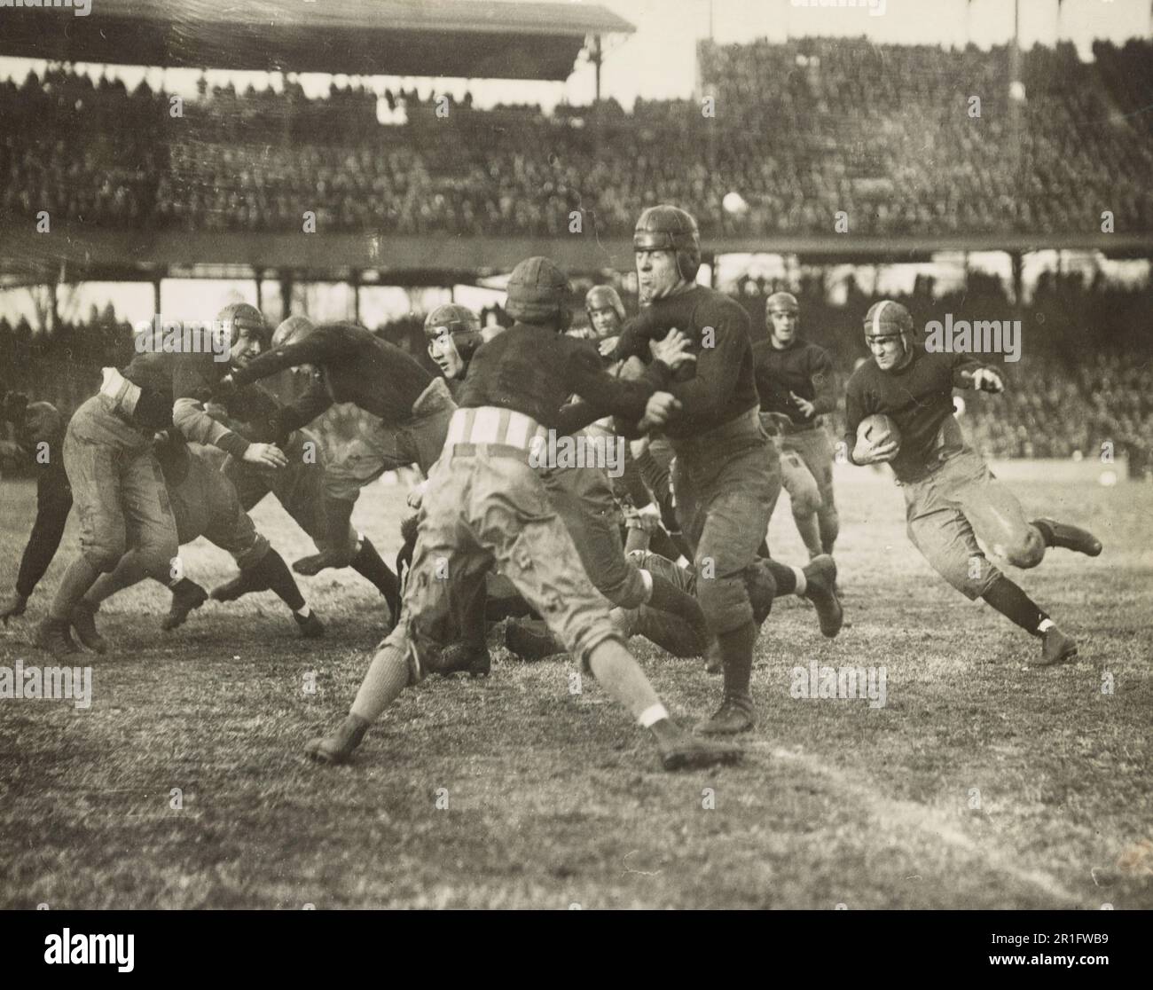 Archivfoto: Zurücklaufen mit dem Fußball, Blocker vor ihm in einem College-Football-Spiel ca. 1920er Stockfoto