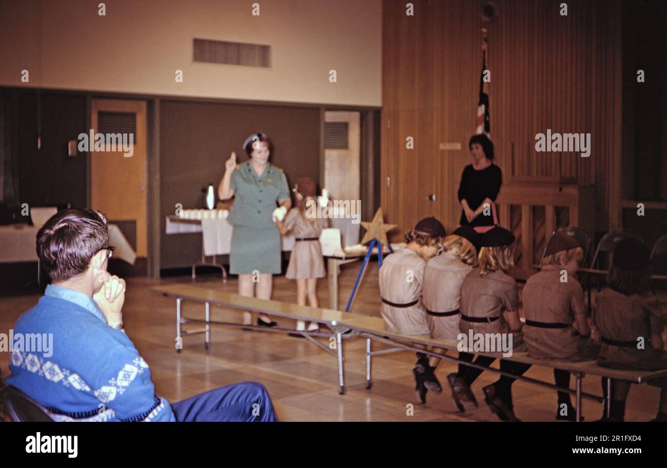 Ein Vater sieht aus wie ein Pfadfindermädchen, das einen Eid von einem Anführer ablegt. 1969 Stockfoto