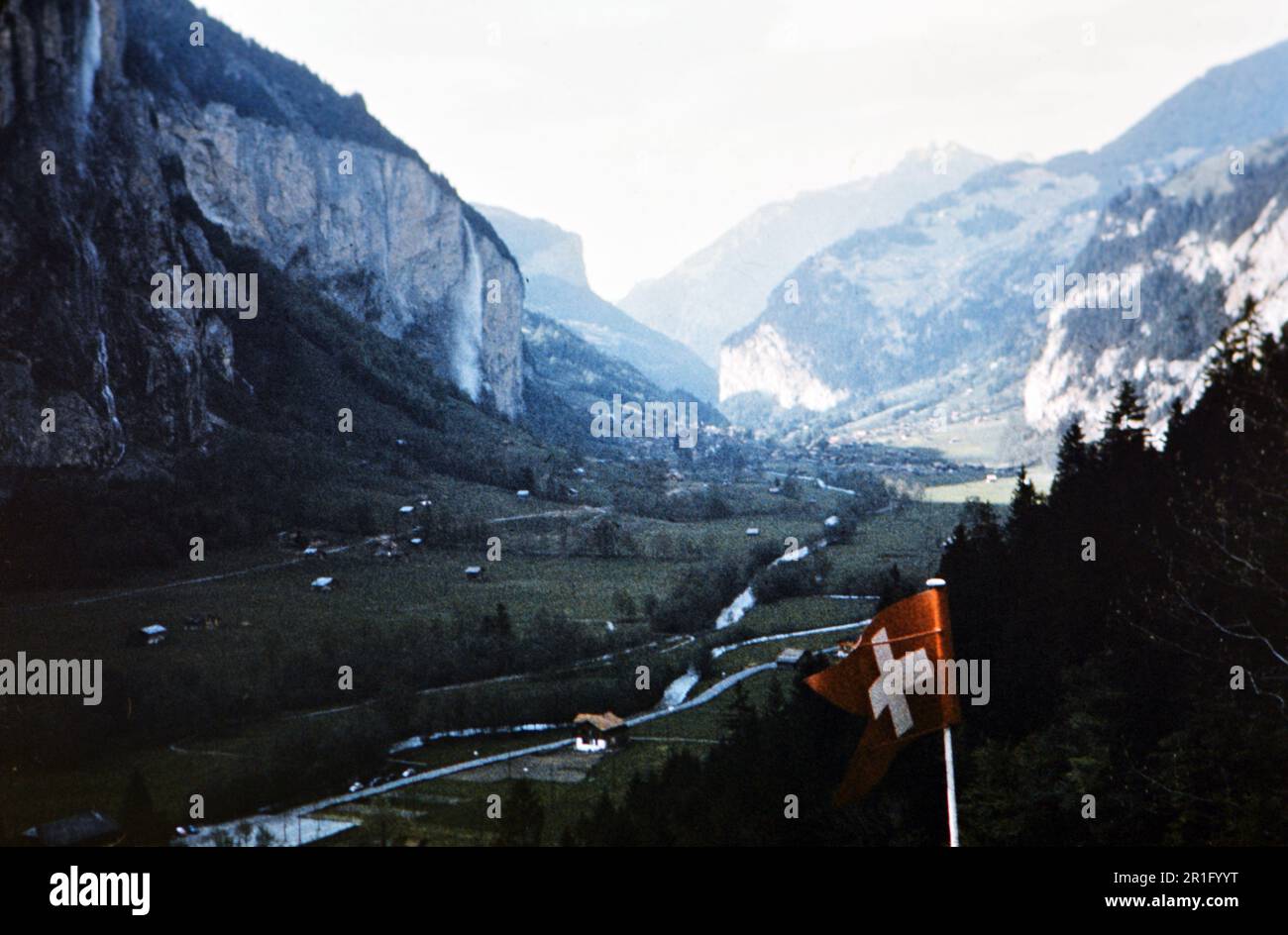 Blick auf ein Tal bei Interlaken Schweiz, Schweizer Flagge im Vordergrund ca. Ca. Mitte 1950er Stockfoto