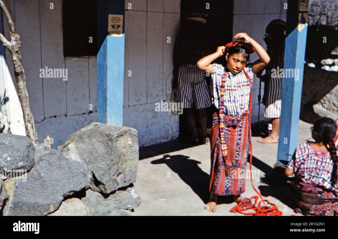 Ein guatemaltekisches Mädchen (Maya), das ein rotes Band in ihr Haar legt. 1962 Guatemala Stockfoto