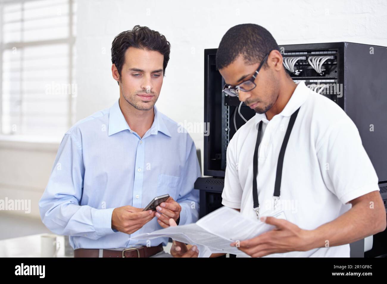 Serverraum, IT-Support und Lesen mit einem Techniker, der mit einem Geschäftsmann für Cybersicherheit zusammenarbeitet. Netzwerk, Datenbank und Anweisungen mit einem Mann Stockfoto