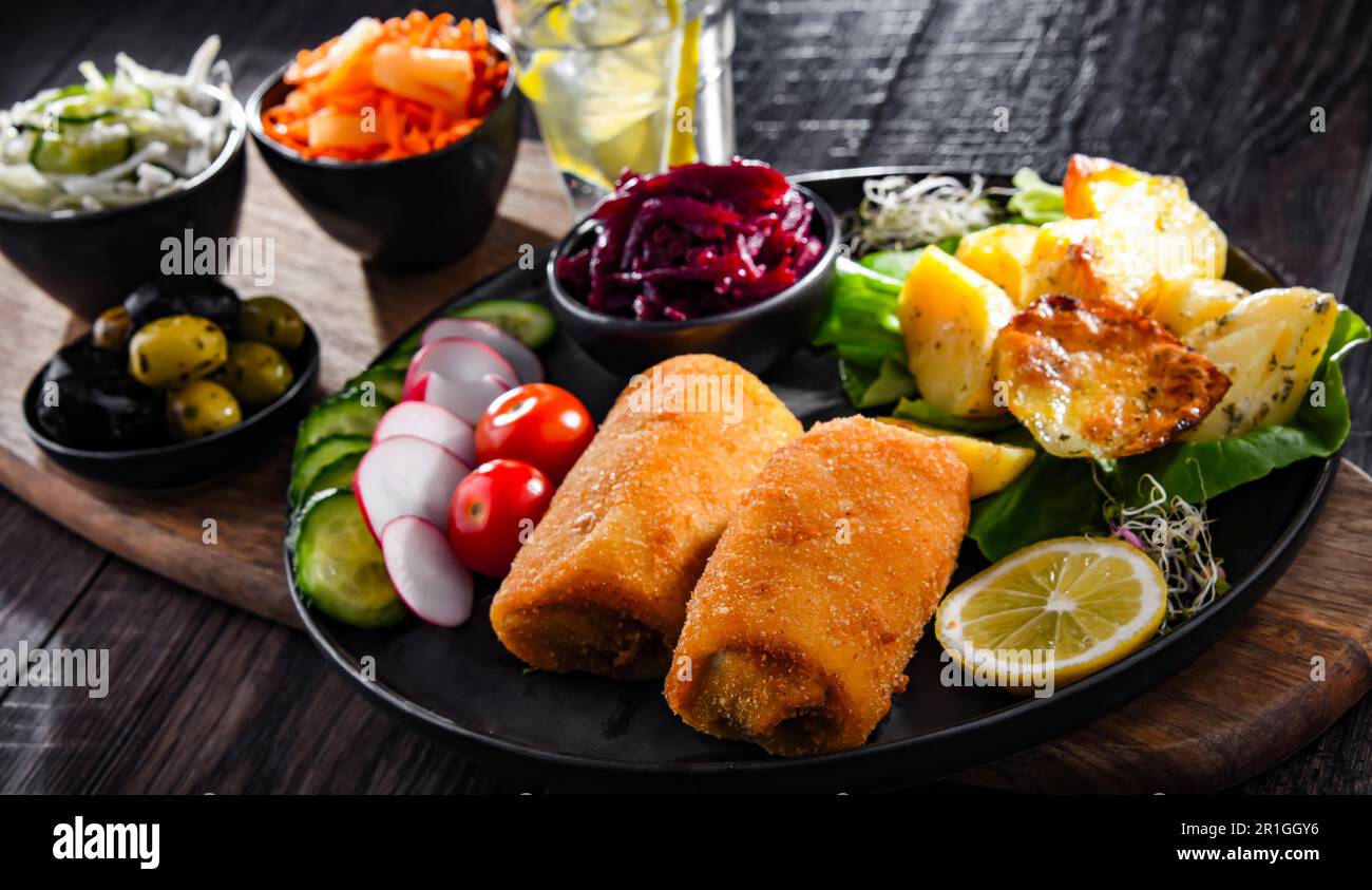 Panierte und frittierte Kroketten mit Kartoffeln und Gemüsesalaten Stockfoto