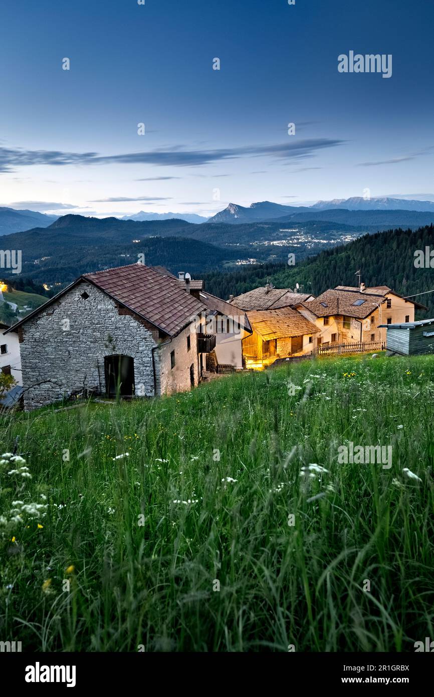 Abenddämmerung im alpinen Dorf Perpruneri. Im Hintergrund das Lavarone-Plateau. Folgaria, Alpe Cimbra, Trentino, Italien. Stockfoto