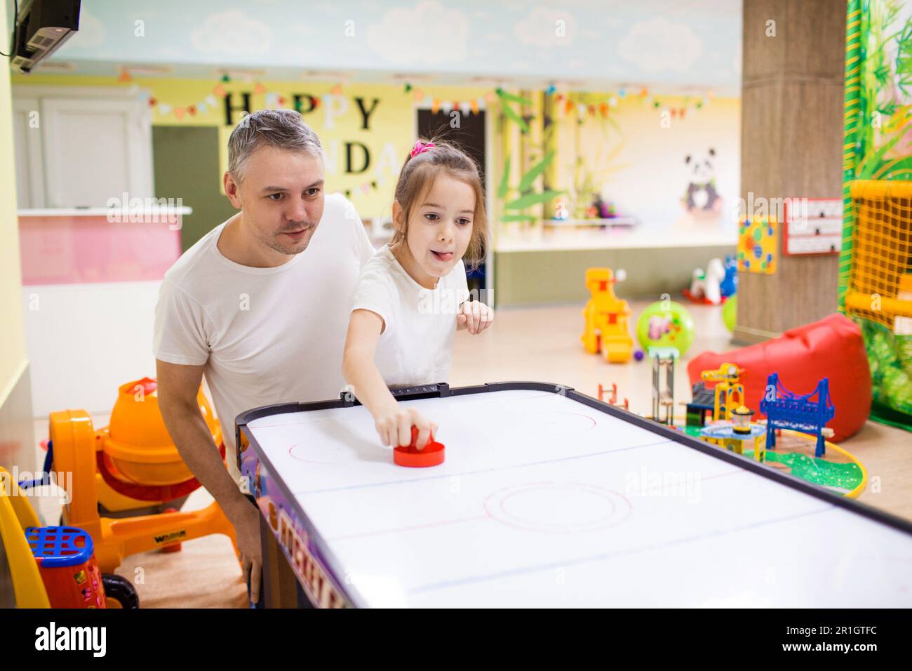 Vater und Tochter haben Spaß und spielen im kreativen Zentrum der Kinder, spielen Airhockey. Stockfoto