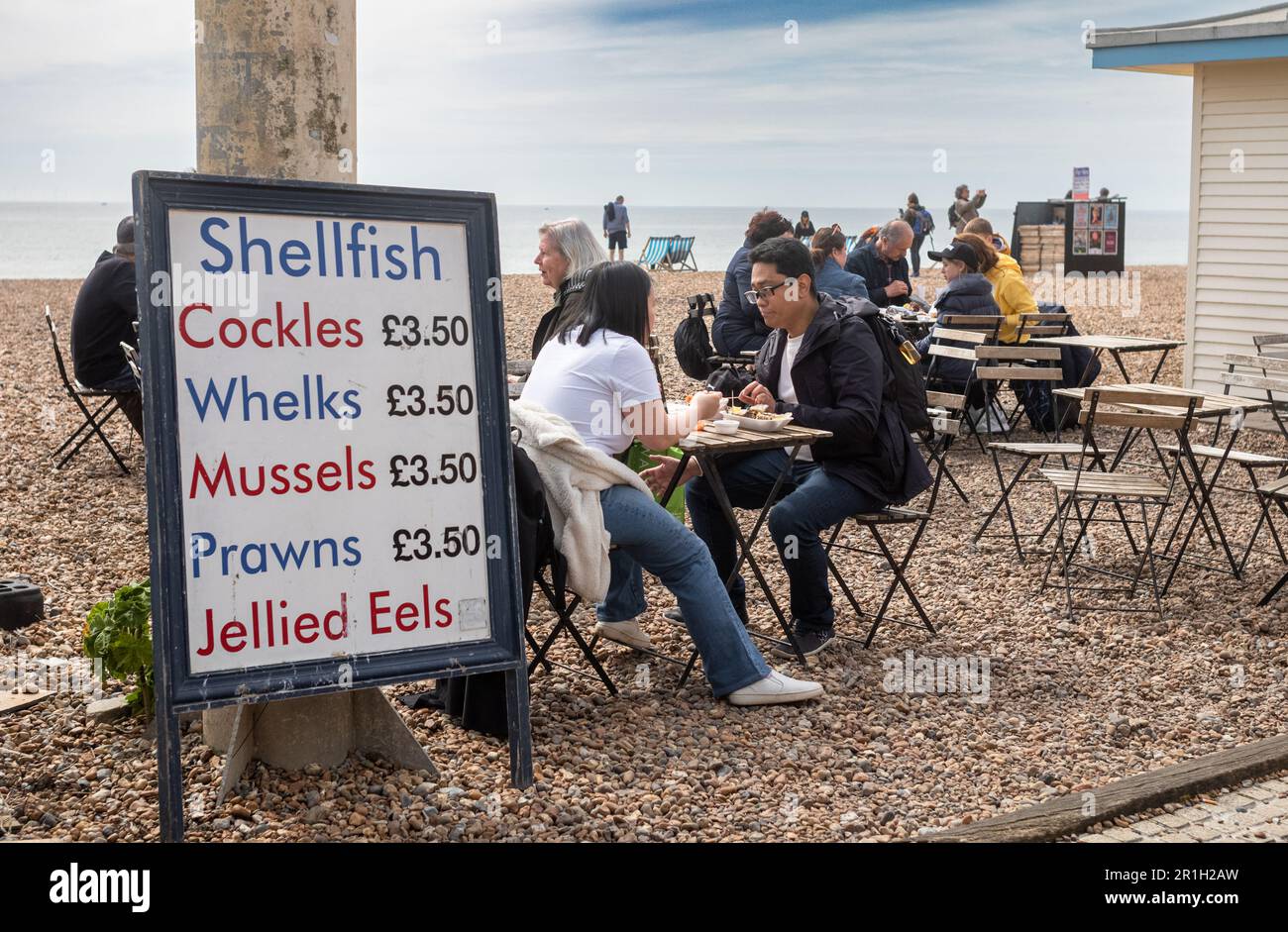 Am Kieselstrand in Brighton, East Sussex, Großbritannien, gibt es neben einer Preisliste traditionelle Schalentiere und Meeresfrüchte zu essen. Brighton, ein lebhafter Vibrationsalarm Stockfoto