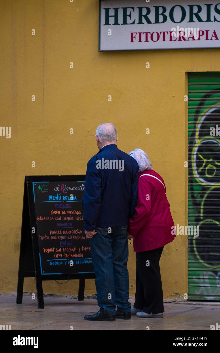 Malaga, Spanien - Nov. 27 2022: Seniorenpaar liest eine Speisekarte eines Restaurants, während es Händchen hält Stockfoto