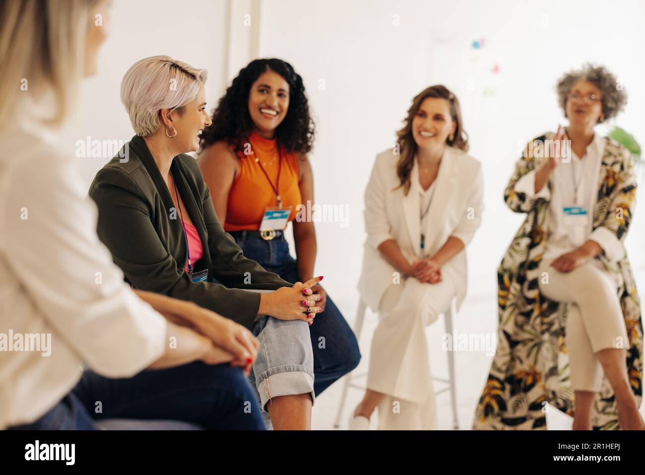 Fröhliche Geschäftsfrauen, die während einer Konferenz an einem modernen Arbeitsplatz diskutieren. Gruppe multikultureller Geschäftsfrauen, die in zusammenarbeiten Stockfoto