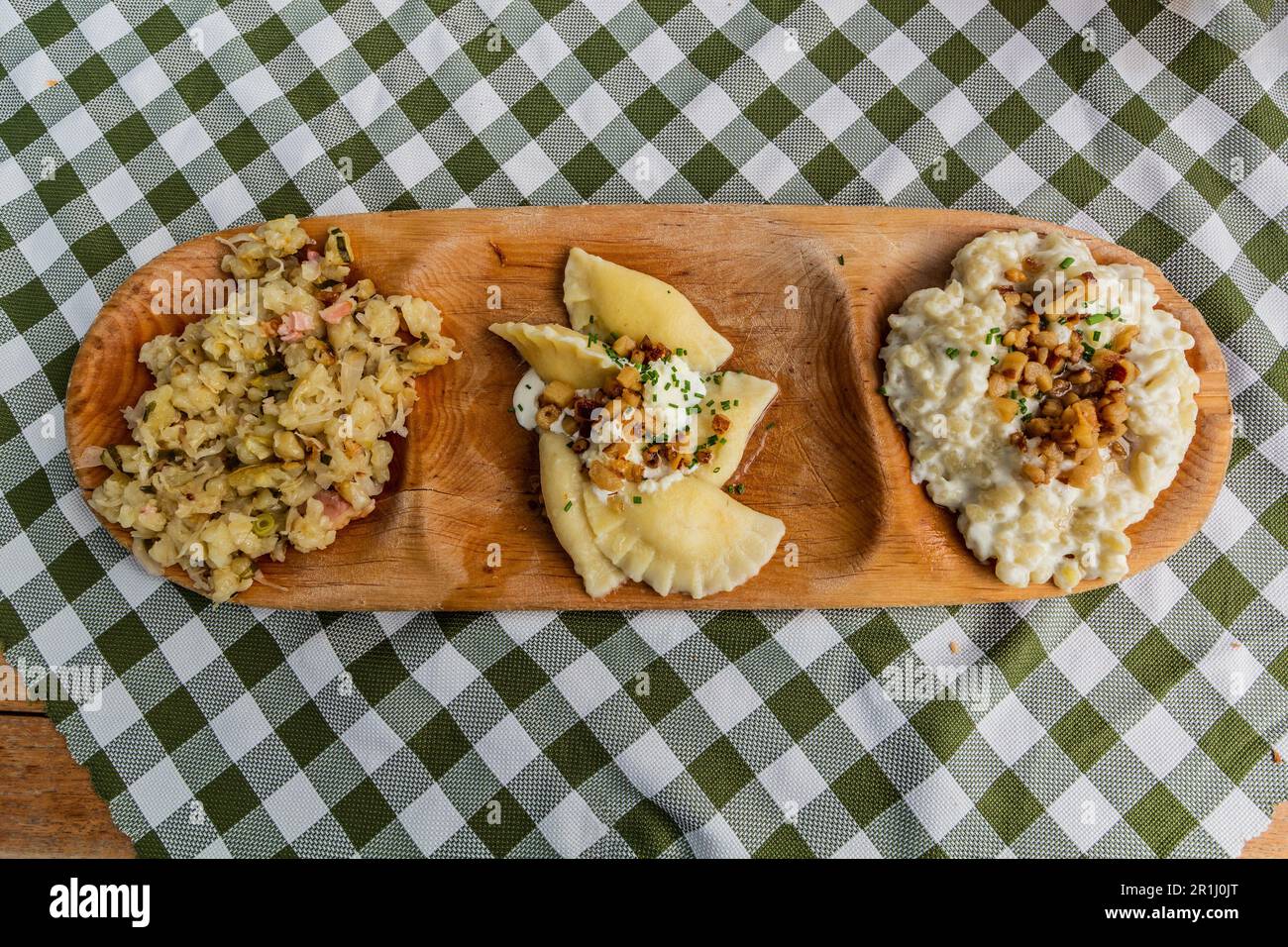 Teller mit traditionellen slowakischen Gerichten - Kapustove Strapacky (Knödel mit Kohl), bryndzove Pirohy (Pirogi mit bryndza Schafskäse) und bryndzove h Stockfoto