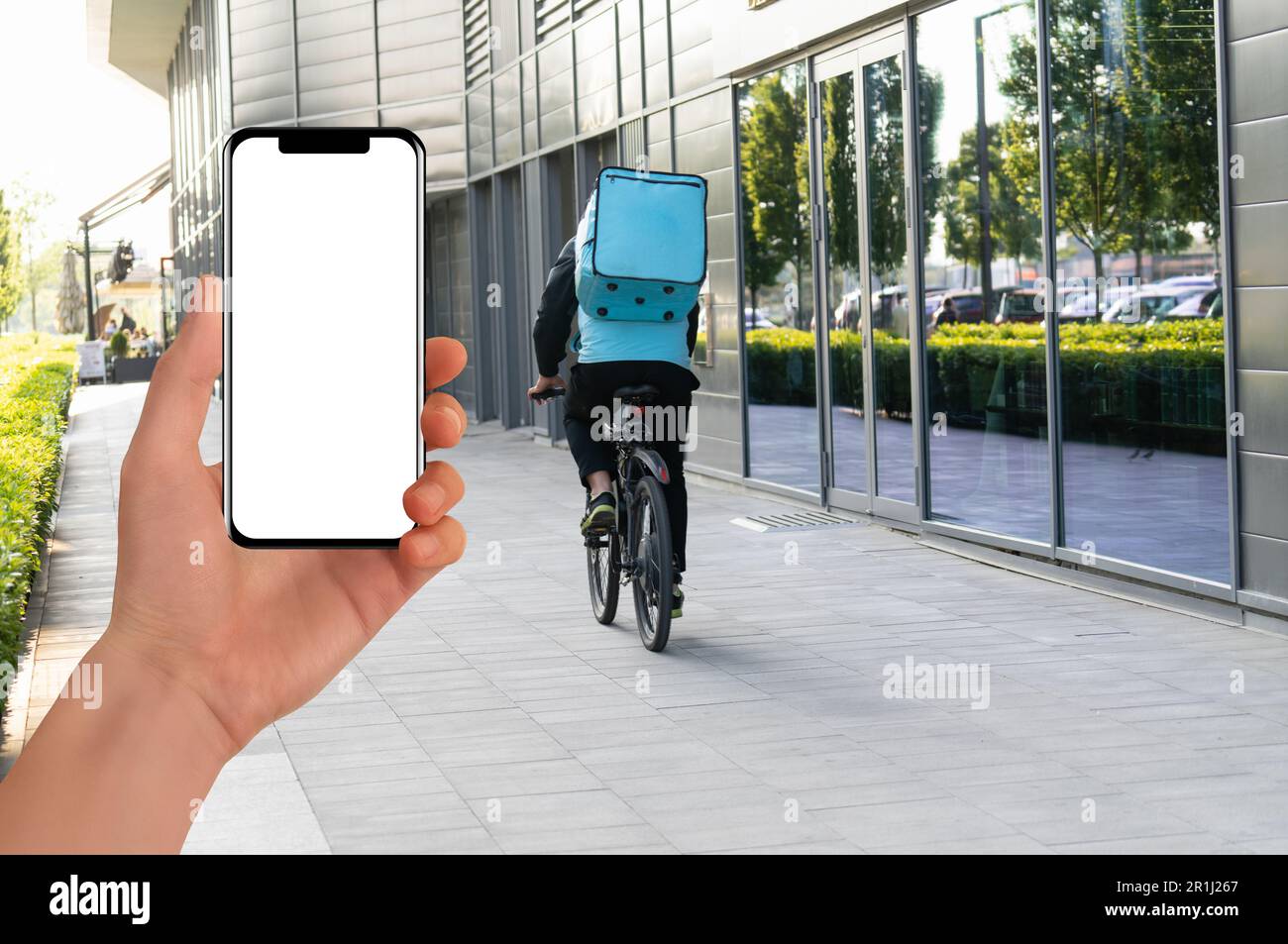 Hand mit Telefon an einem Background Delivery Kurier auf einem Motorrad. Mobile Anwendung für Lebensmittellieferungen. Hochwertiges Foto Stockfoto