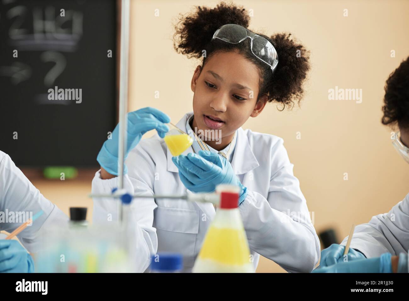 Porträt eines schwarzen Teenager-Schulmädchens, das wissenschaftliche Experimente in der Schule genießt und mit chemischer Reaktion arbeitet Stockfoto