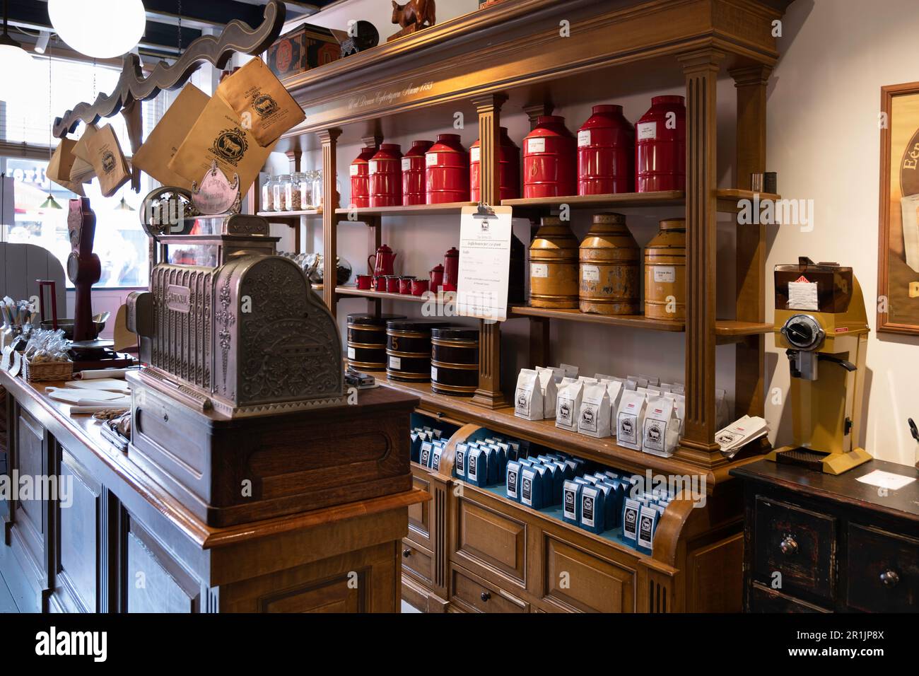 Alte klassische Kasse und Retro-Kaffeebehälter auf Holzregalen im Douwe Egberts Coffee Museum, Teil des Museum Joure, Niederlande Stockfoto