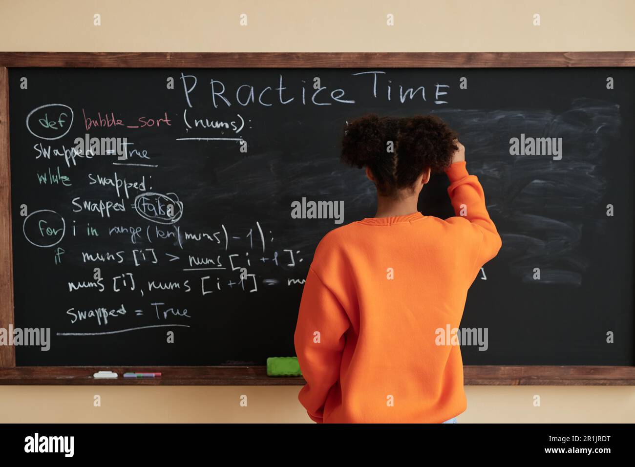 Rückansicht eines schwarzen Teenagers, das an der Tafel in der Schule schreibt, Kopierraum Stockfoto