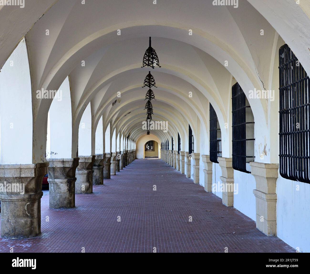 Bogengang im ersten Stock des Gebäudes. Straßenlaternen an der Gangdecke. Gitter an den Fenstern Stockfoto