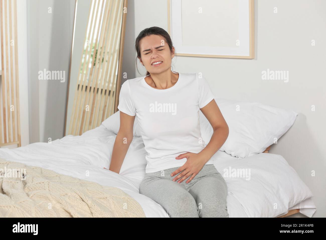 Junge Frau mit Zystitis im Bett zu Hause Stockfoto