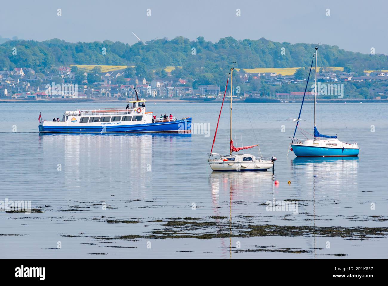 Festgetätete Segelboote und Touristenboote in ruhigem Wasser an einem sonnigen Tag, Firth of Forth, Schottland, Großbritannien Stockfoto