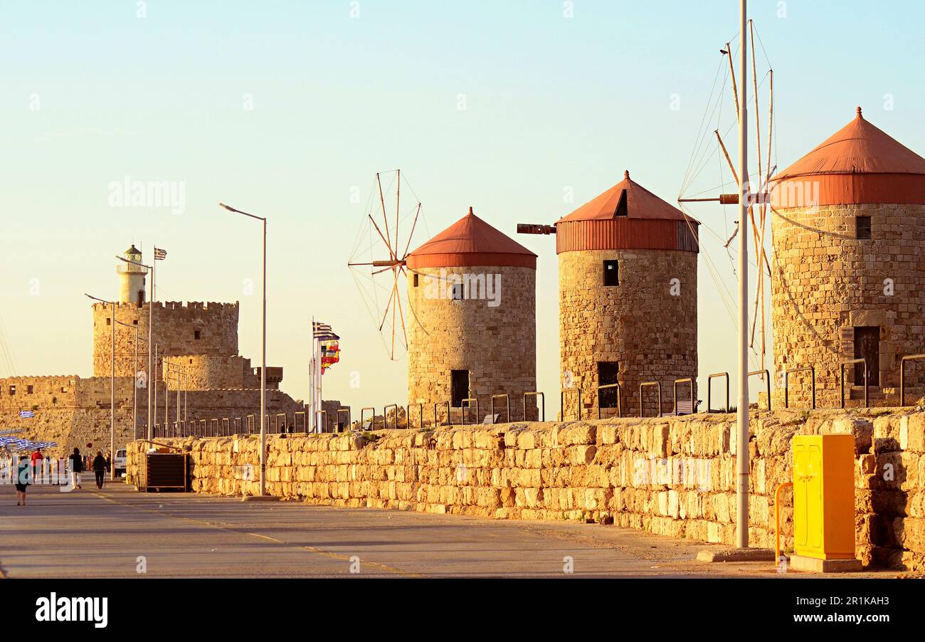 Drei mittelalterliche Windmühlen aus Stein mit roten Dächern. Die Festungsmauer um den Leuchtturm von St. Nikolaus. Flaggen verschiedener Länder entlang des Ufers Stockfoto