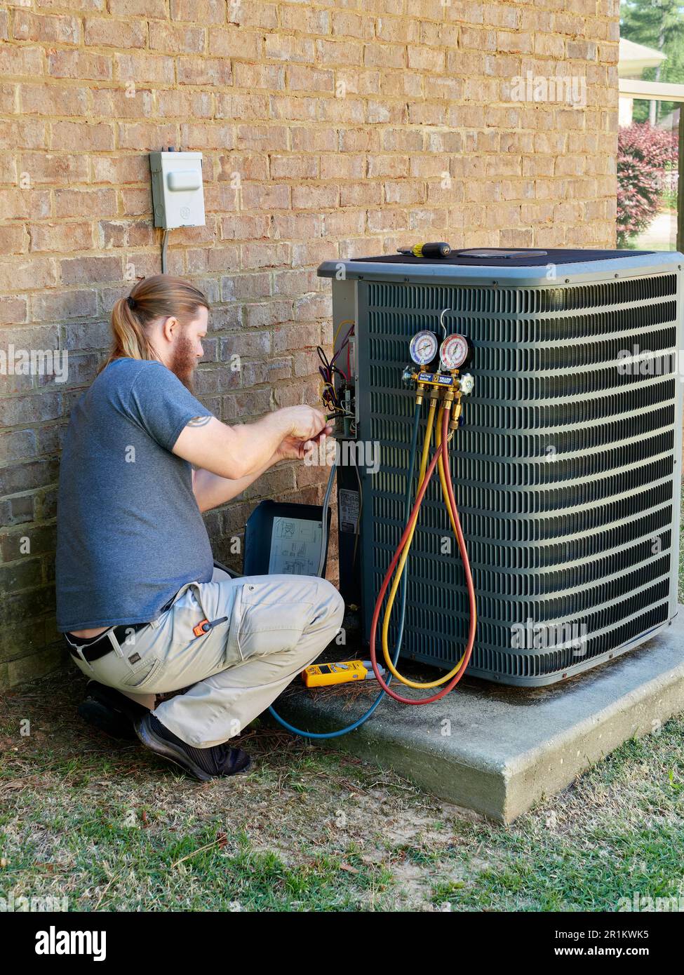 Klimaanlagen-Techniker oder -Techniker, der an einer Außenklimaanlage in Alabama, USA, arbeitet. Stockfoto