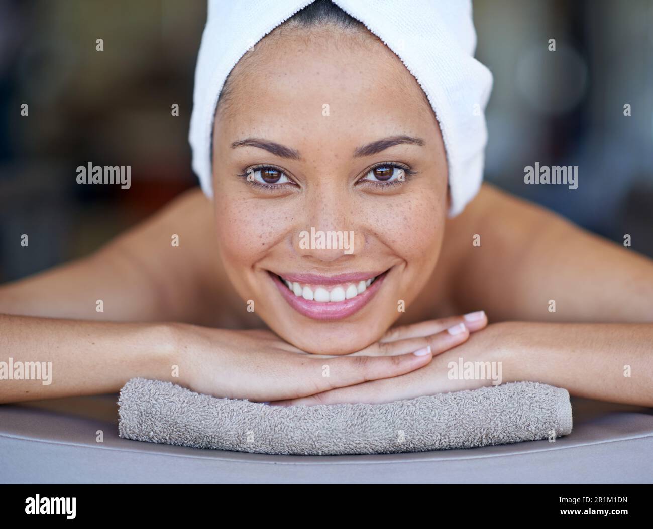 Komm mit mir auf eine Massage. Porträt einer jungen Frau, die auf einem Massagetisch liegt. Stockfoto