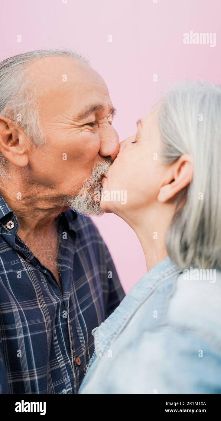 Glückliches Seniorenpaar, das sich im Freien in Liebe küsst - fröhliches Konzept für ältere Menschen und Familienleben - weicher Fokus auf die Männernase Stockfoto