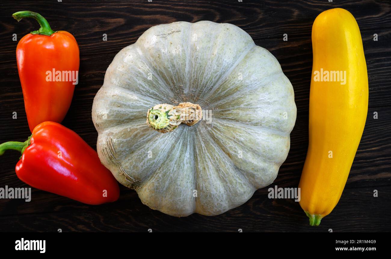 Gemüsemark, Kürbis und süßer Pfeffer auf dunklem Holztisch, Draufsicht. Stillleben von Bio-Lebensmitteln, weißer Kürbis und Zucchini, flach liegend. Ernte, Stockfoto