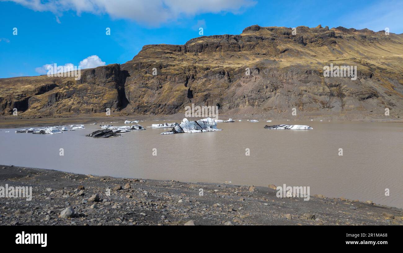 Eine malerische Szene eines ruhigen Sees mit mehreren großen, gebogenen und zerklüfteten Eisstücken, die im Wasser schweben Stockfoto