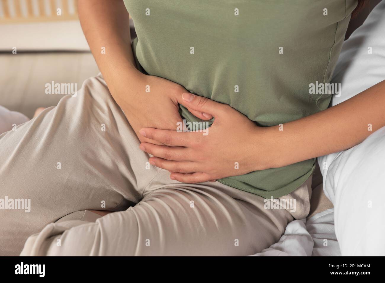 Junge Frau, die an Zystitis im Bett leidet, in geschlossenen Räumen Stockfoto
