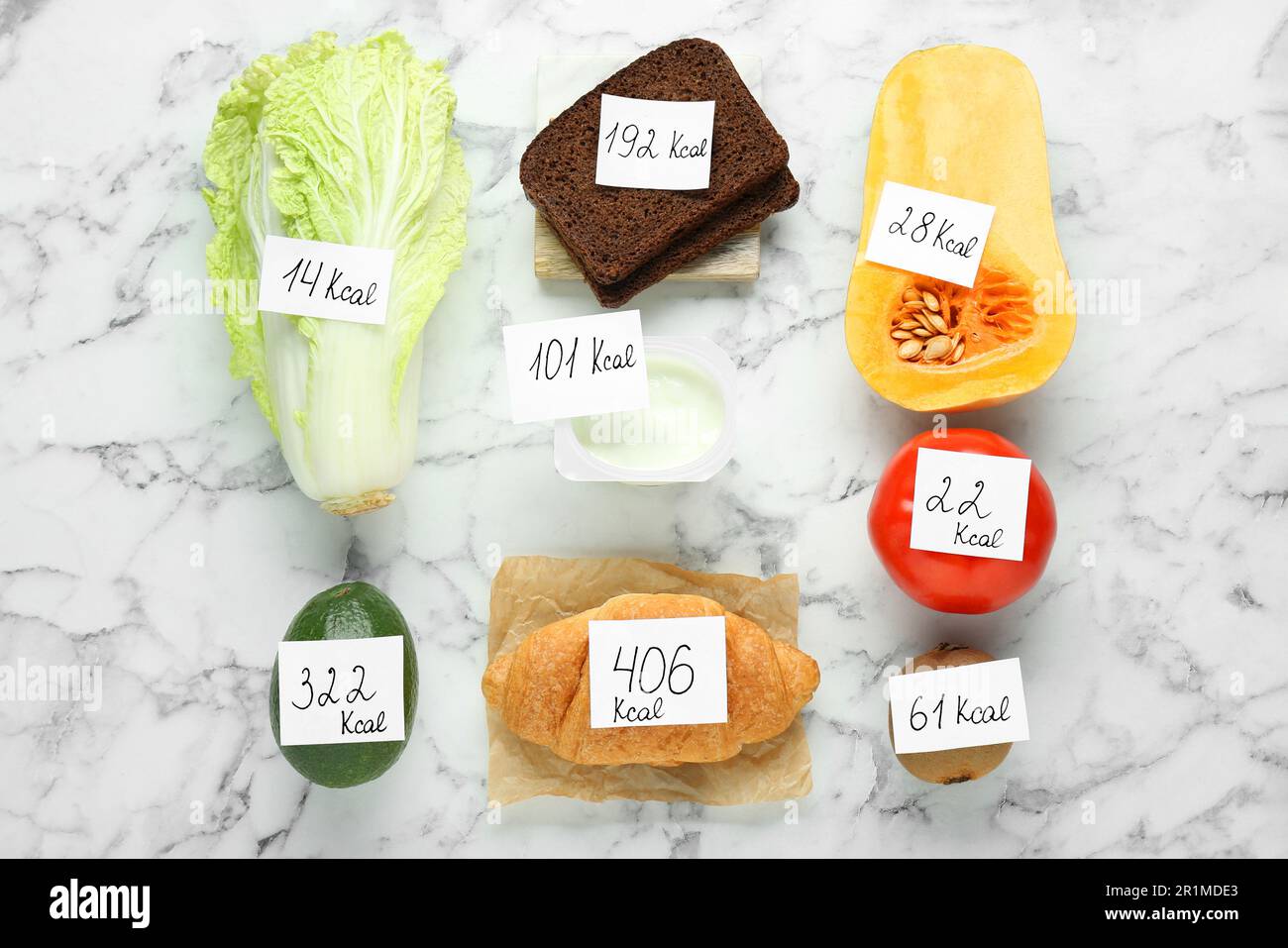 Lebensmittelprodukte mit Heizwertanhängern auf weißem Marmortisch, flach liegend. Gewichtsverlust-Konzept Stockfoto