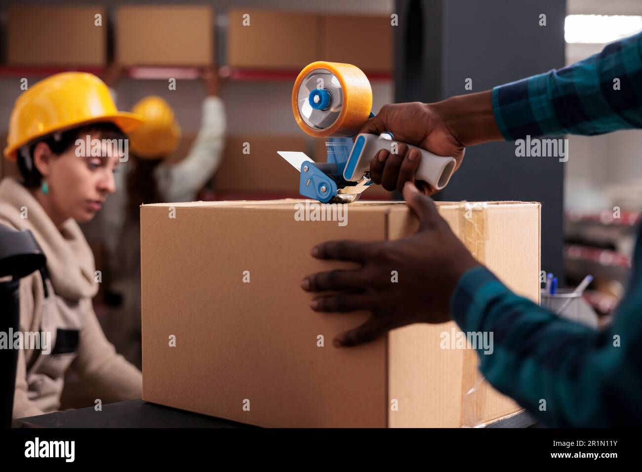 Zustellleiter verpackt das Paket mit einem handgeführten Abroller Stockfoto